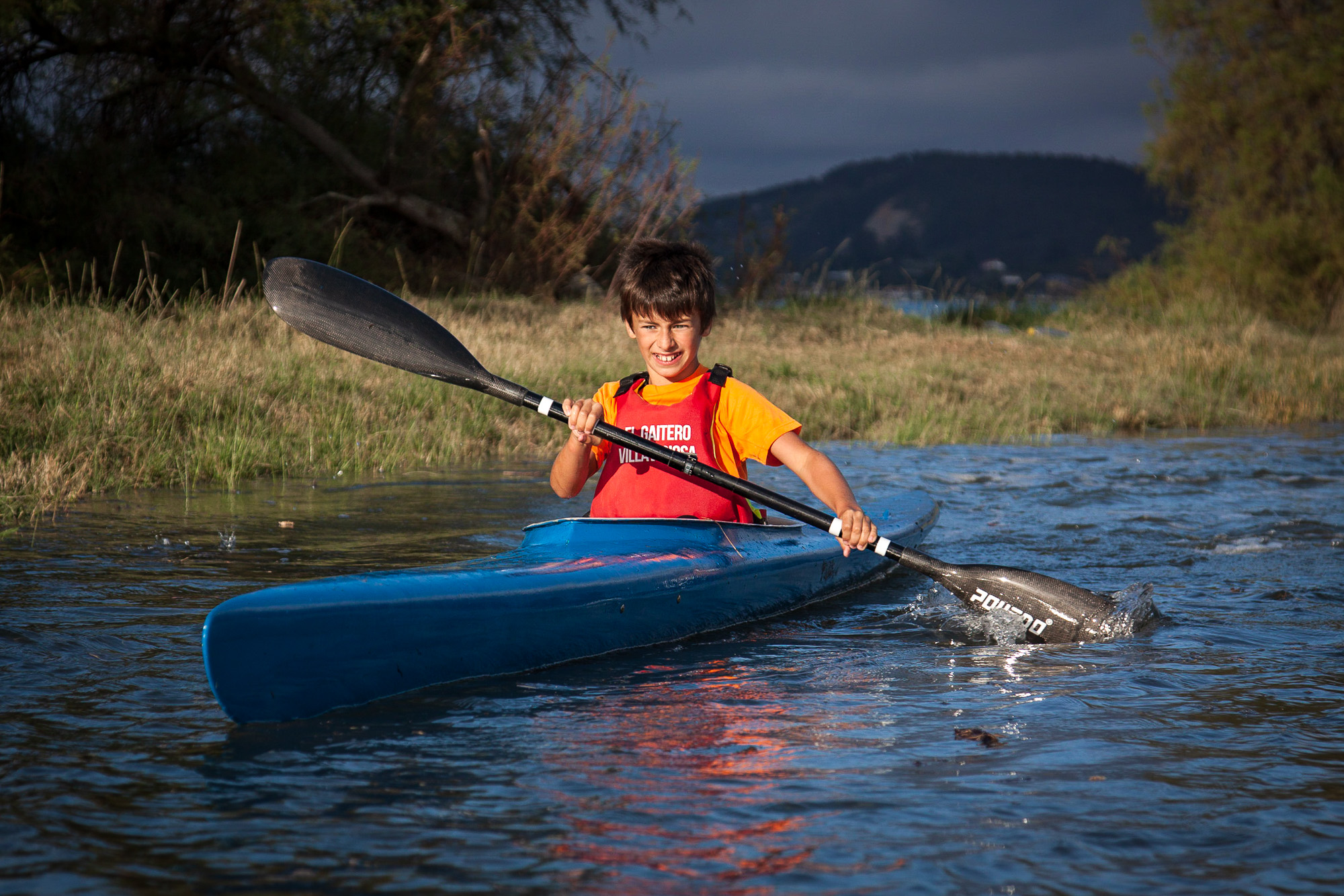 Mateo Alonso de niño remando en una piragua azul en el río